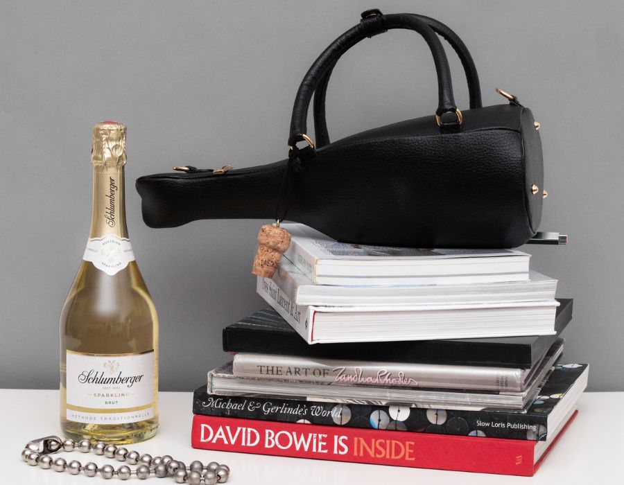 Wendy Jim Tasche und eine Flasche Sparkling neben Bücher