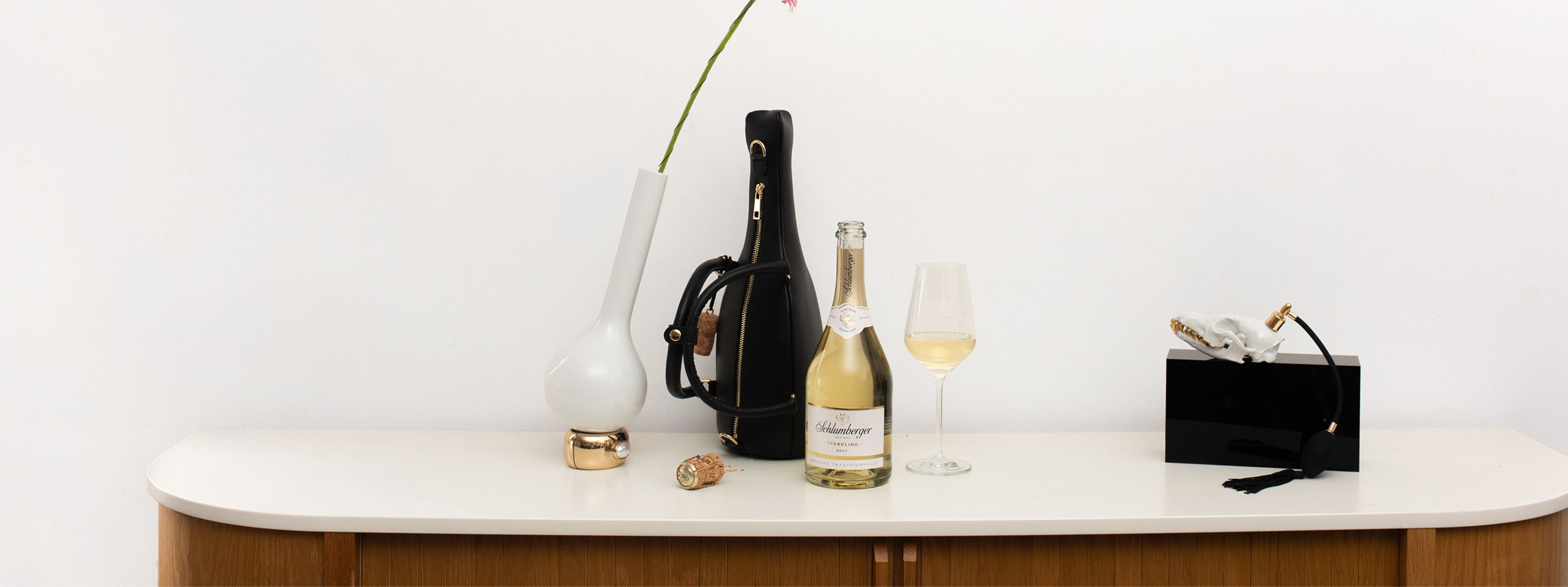Sparkling Brut Flasche und Tasche stehen auf Kommode