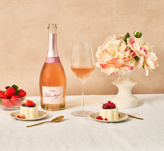 Pinot Noir steht auf einem Tisch, daneben ein eingefüllte Glas und zwei Panna Cotta mit Früchten