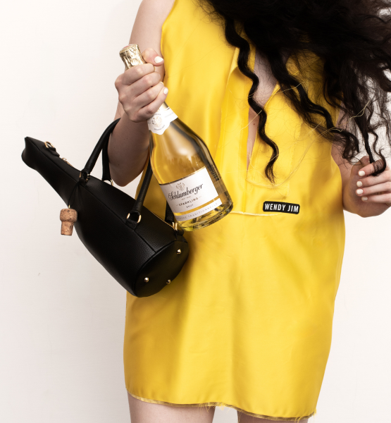 Dame im gelben Kleid trägt Schlumberger Sparkling und Sparkling Bag in der Hand